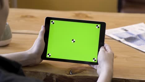 persona que sostiene la tableta con pantalla verde