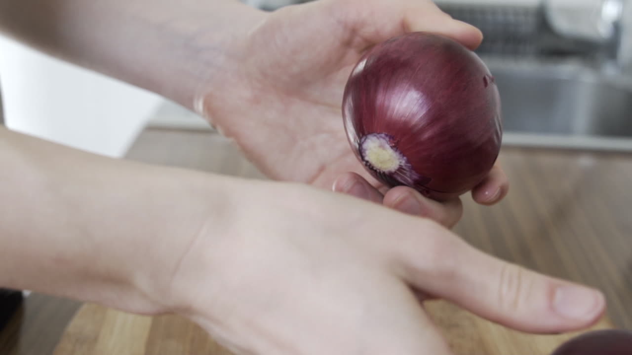 Slow motion as hands peeling off a purple onion in the kitchen