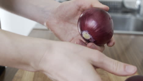 Slow-motion-as-hands-peeling-off-a-purple-onion-in-the-kitchen