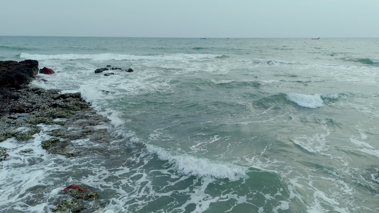Onde che si infrangono sugli scogli della riva del mare.
