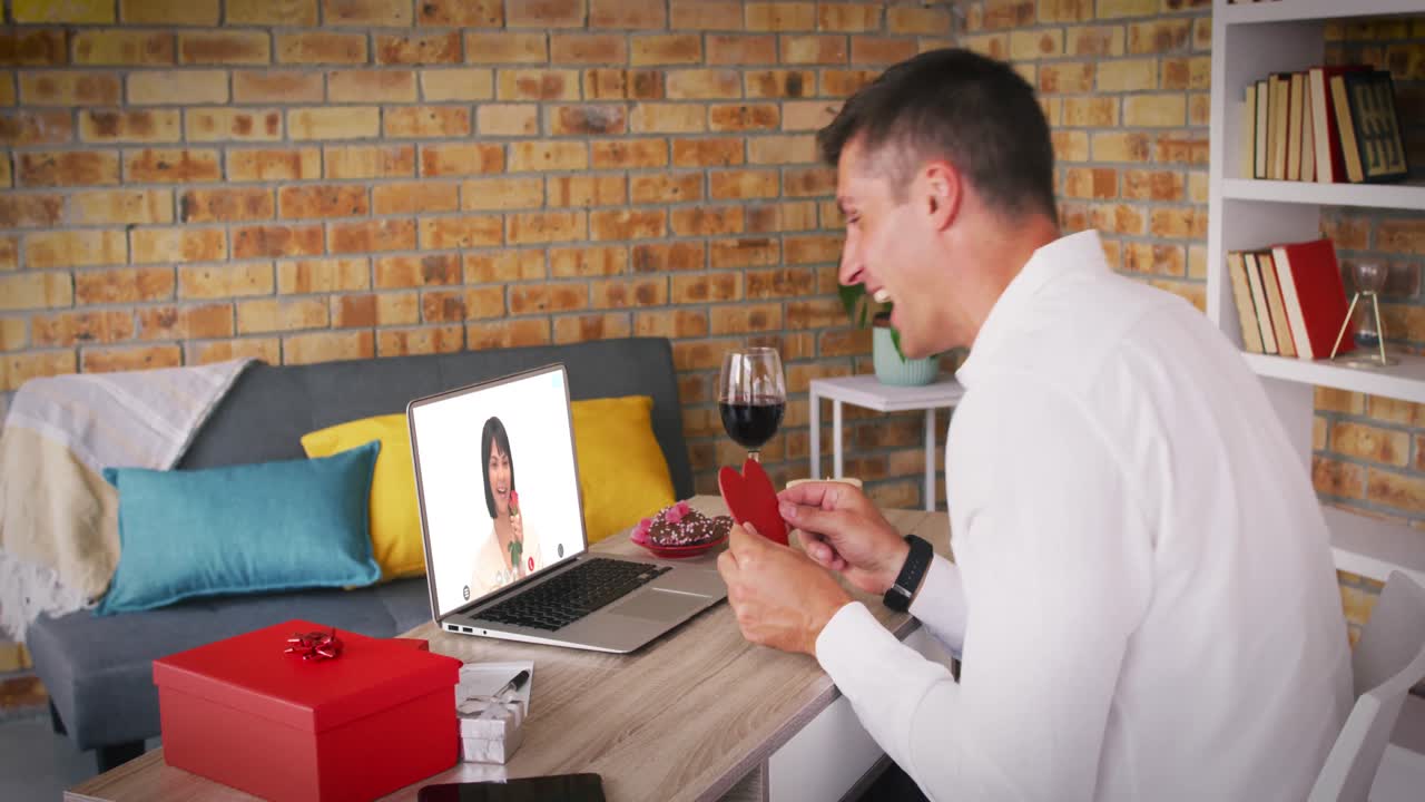 다양한 커플이 발렌타인 데이트를 하고 있습니다. 비디오 통화 남자가 노트북 화면에서 여자에게 키스를  ⁇ 습니다.