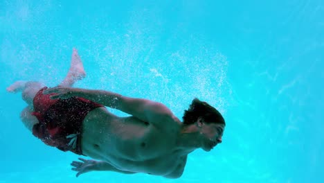 Hombre-En-Forma-Nadando-Bajo-El-Agua-En-La-Piscina