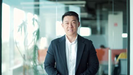 close up portrait confident successful happy asian business man in formal suit looking at camera and smiling indoors modern office. face male businessman worker,