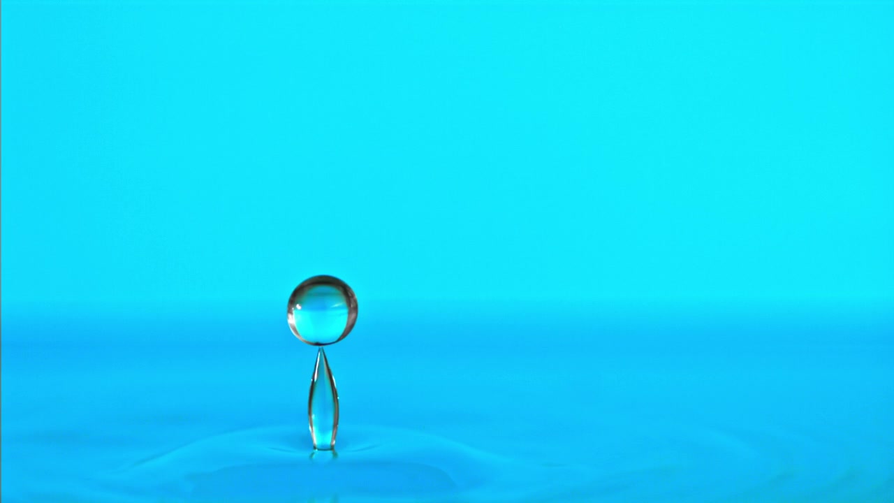 Goccia d'acqua che cade e schizza al rallentatore su una superficie blu