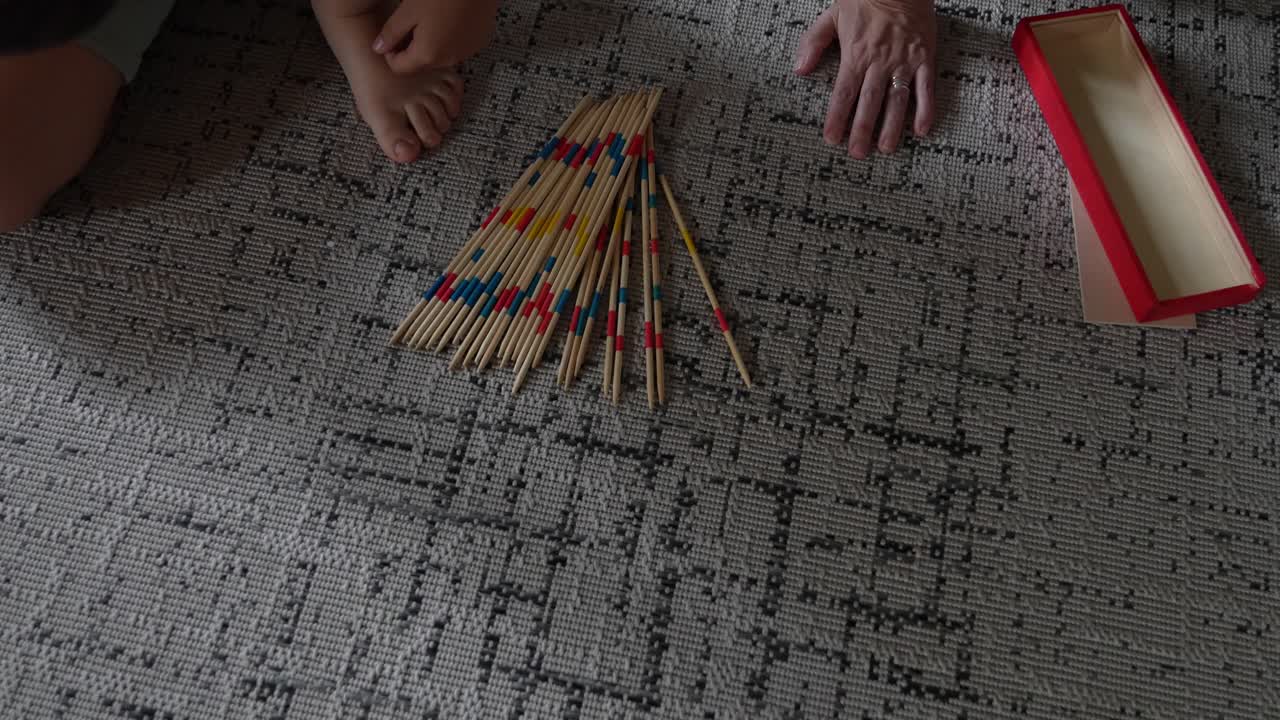 People playing pick up sticks on a rug