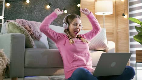 young beautiful teenager raises her hands up looking forward to successful and good email news looking at laptop. concept of success and victory