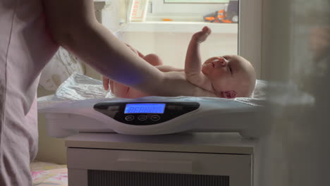 mutter wiegt das baby mit einer elektronischen waage