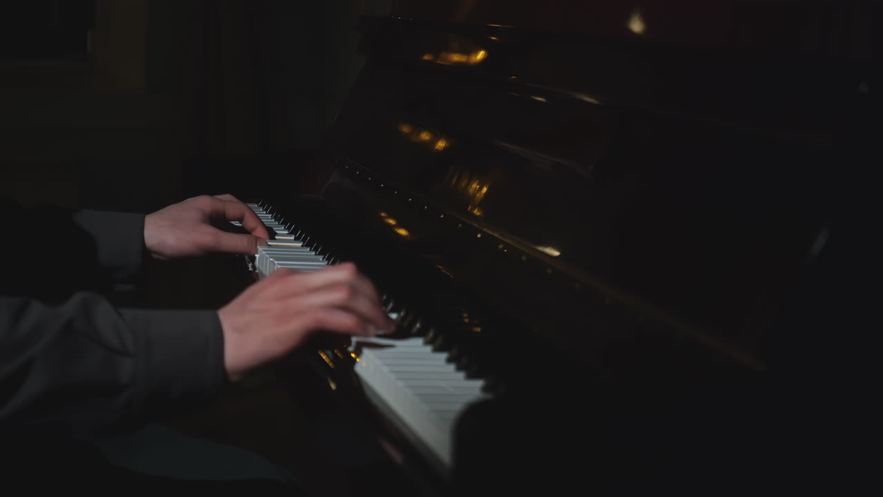 persona tocando el piano en una habitación oscura