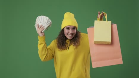 woman holding dollar banknotes and showing her shopping bags