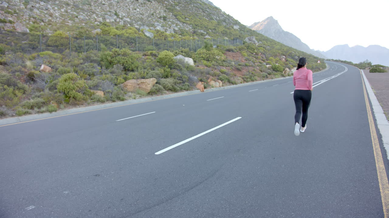 Running on mountain road, woman exercising in nature with scenic view, copy space