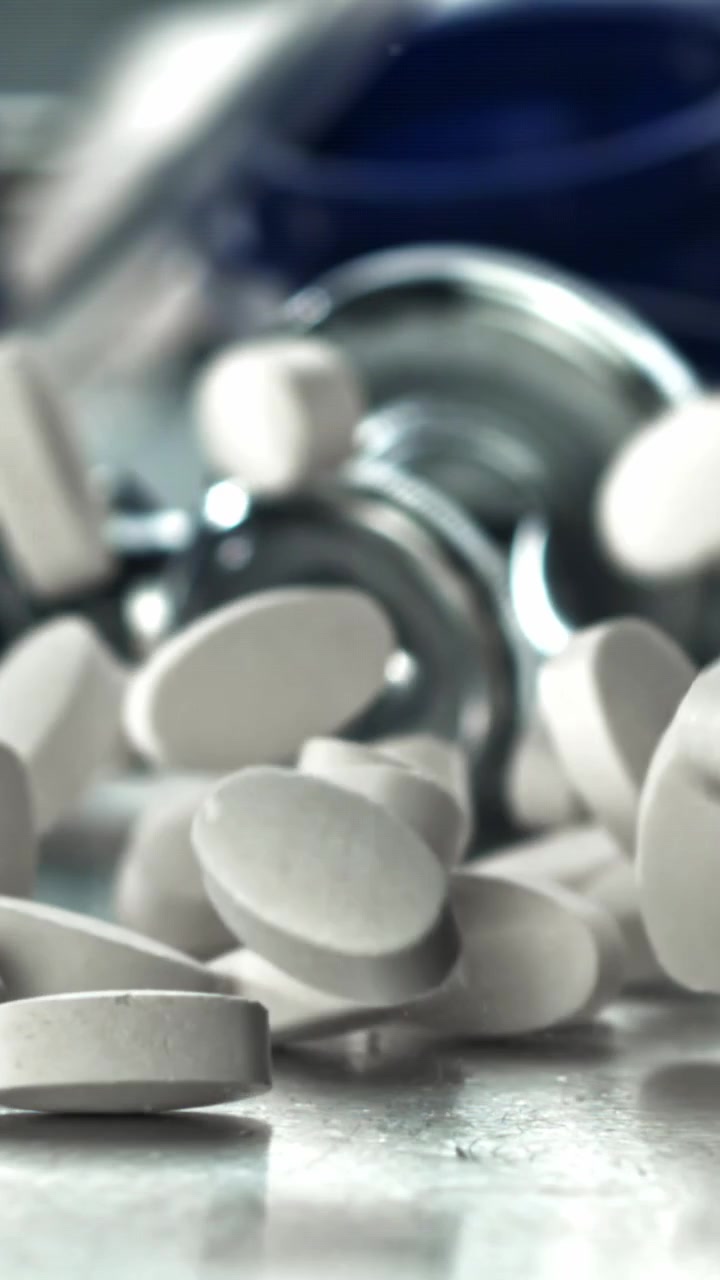 Pillole mediche bianche che cadono al rallentatore con uno stetoscopio sullo sfondo