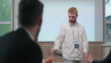 un carismático experto en negocios está hablando en un seminario educativo para gerentes y especialistas en tecnología de la información.