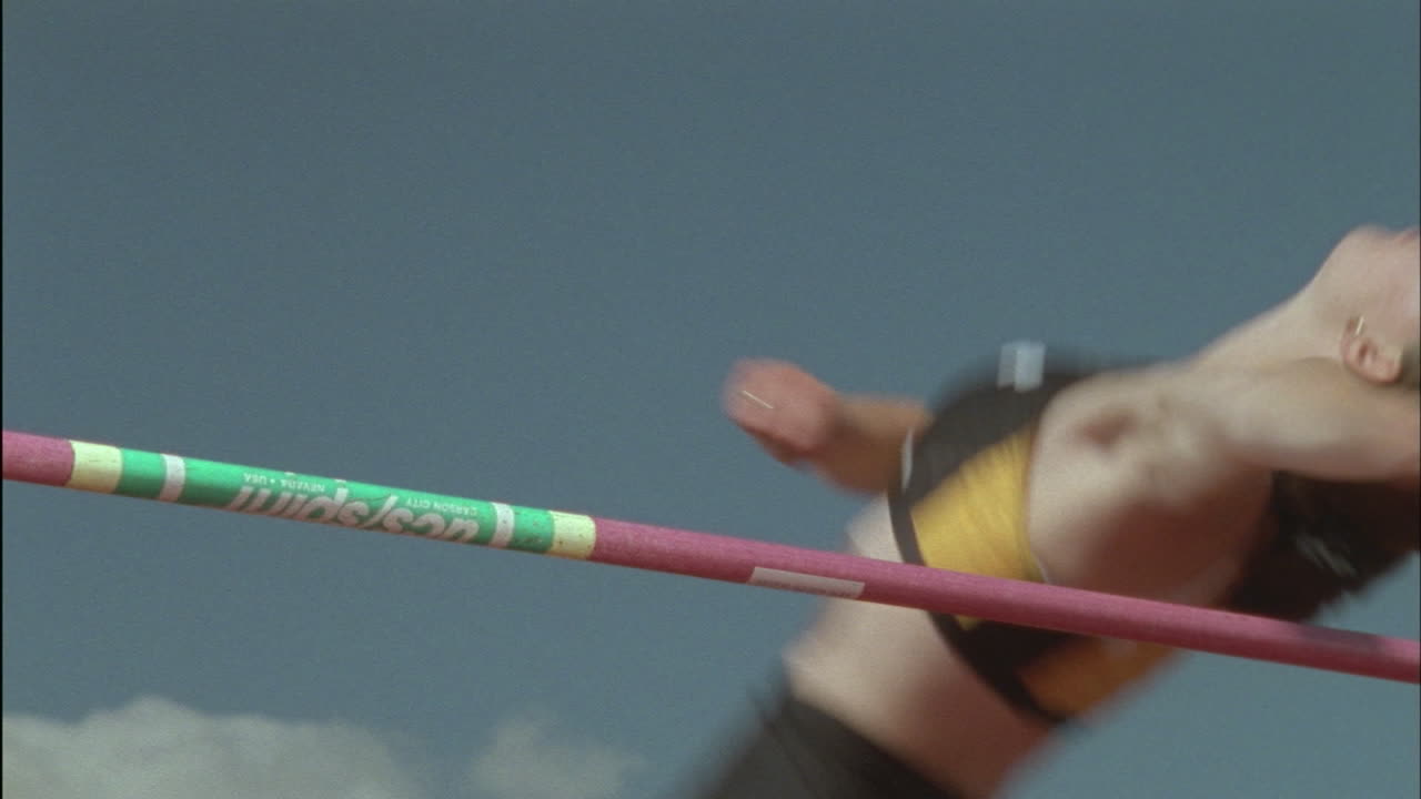 una mujer joven salta alto sobre un poste