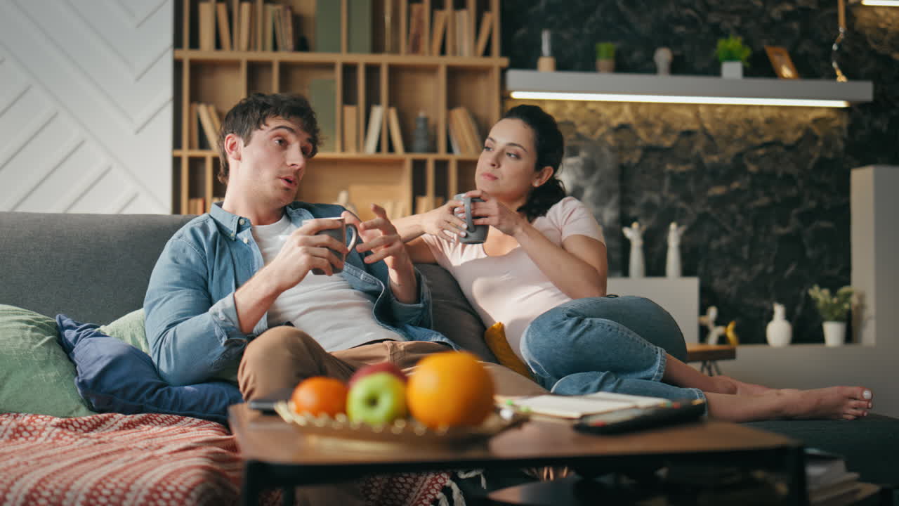 커피와 함께 휴식을 취하는 부부 휴식 소파 쾌적한 주말 저녁. 배우자 대화