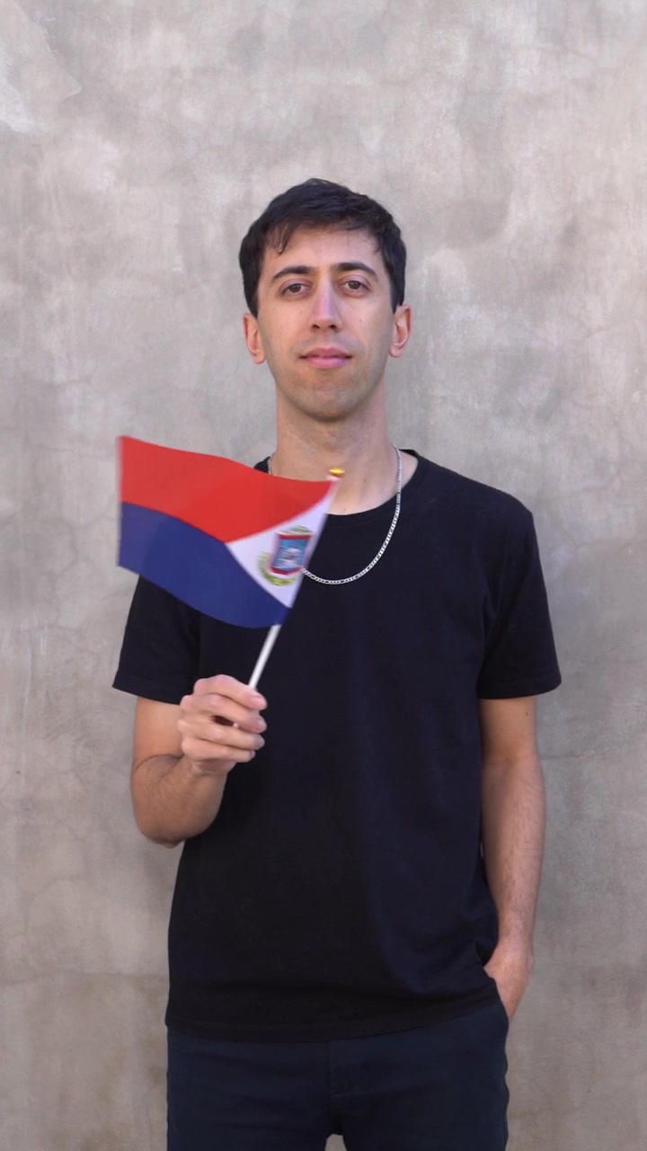 Pria mengibarkan bendera Sint Maarten. Konsep patriotisme. Bidikan vertikal. Gerak lambat