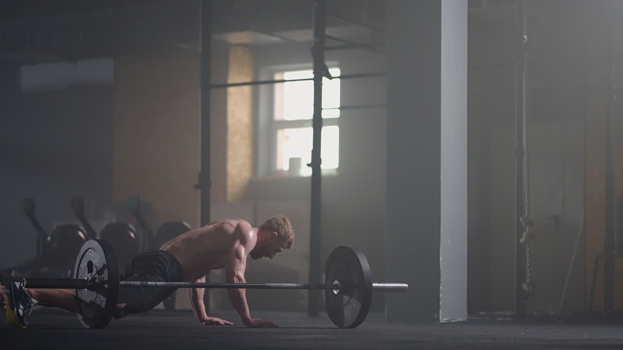 체육관에서 버피 운동을 하는 피트니스 남자. 젊은 남자가 슬로우 모션으로 부시업과 점프 운동을 하는 중간  ⁇ . 스포츠 개념