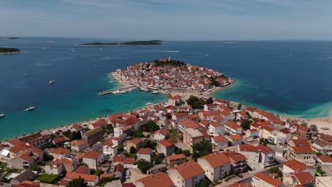 aerial view of primošten, croatia with red rooftops, blue sea, and scenic coastline. historic town