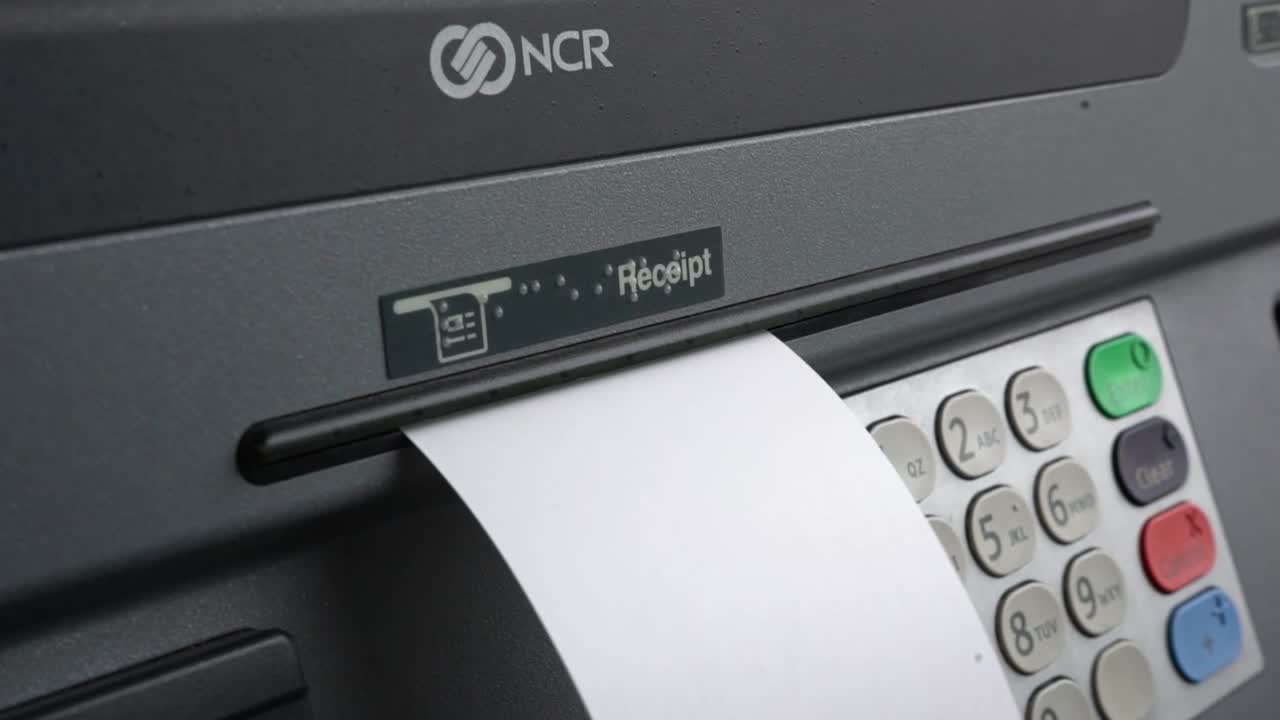 recibo que sale de un cajero automático para un cliente