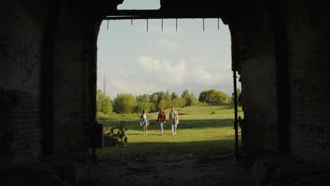 tres personas caminando a través de un arco en un edificio abandonado