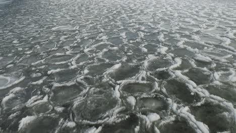 waves rippling ice sheets over water aerial