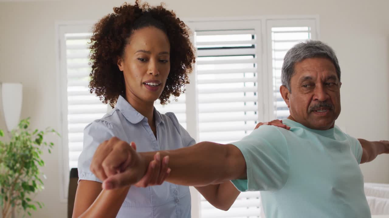 Mixed race female physiotherapist helping senior man stretching his arms