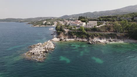 Vista-Aérea-De-La-Costa-De-Kassiopi,-Casas-De-Lujo-Frente-Al-Mar-Junto-Al-Mar-Turquesa,-Isla-De-Corfú,-En-órbita