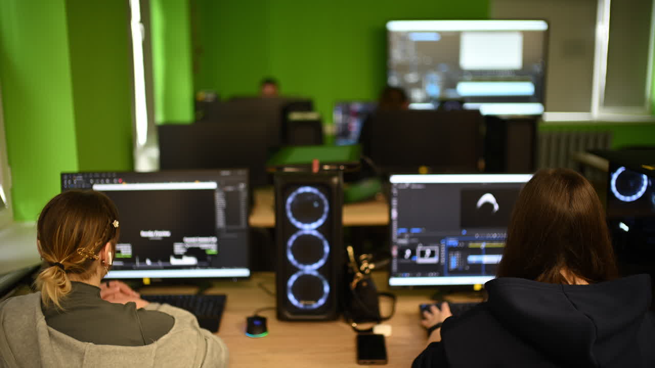 Modern computer classroom with multiple workstations, screens and students working