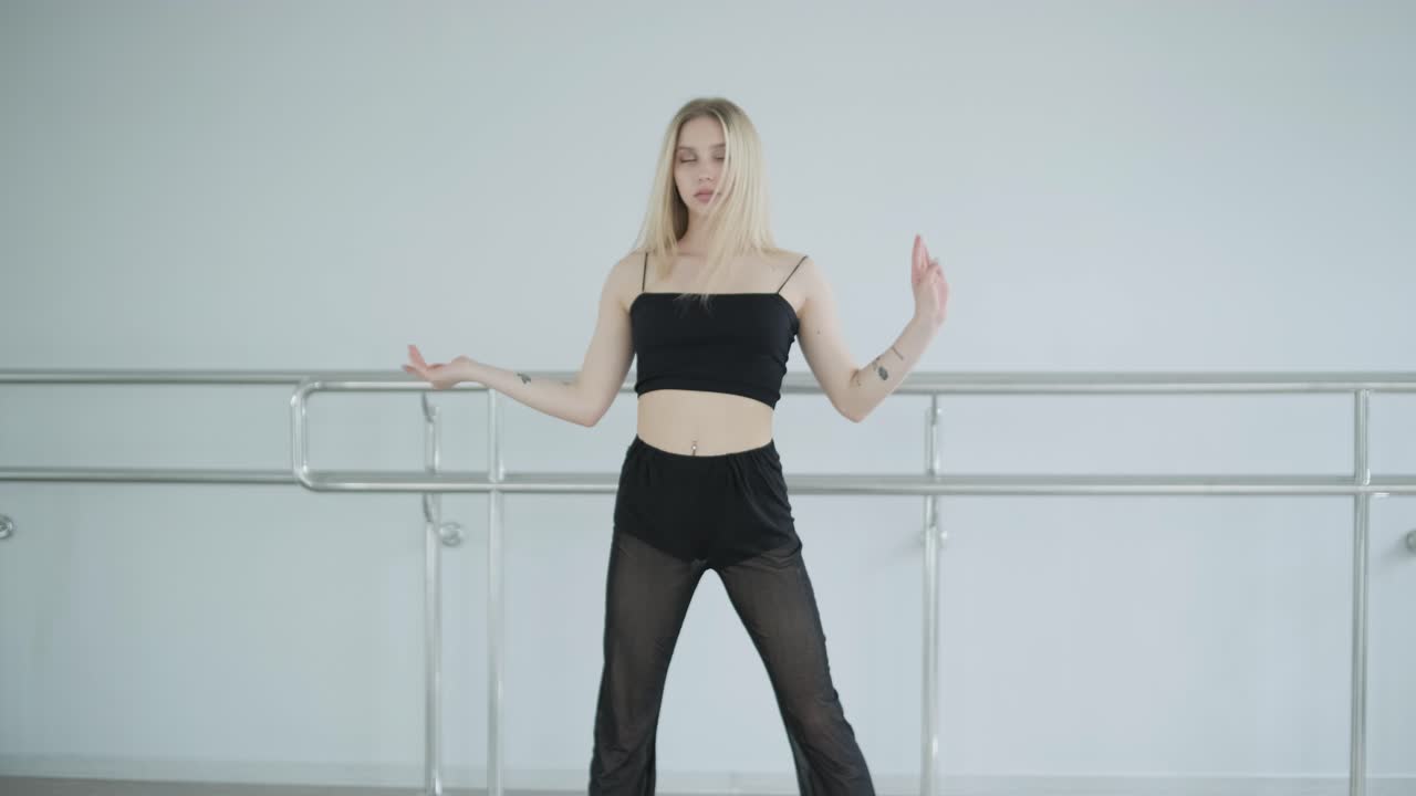 흑색 옷을 입은 소녀가 동시대를 선보이며, 여성 댄서가 하 방에서 흐르는 움직임, 몸과 손의 파동을 보여줍니다. 현대 발레 댄스 안무. 젊은 여성이 부드럽게 움직이고 있습니다.