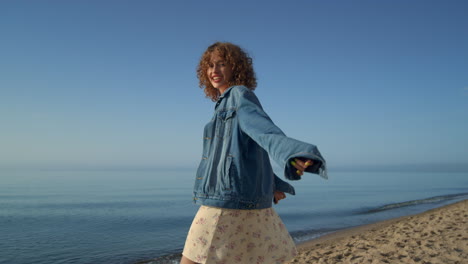 attractive girl enjoying sunny day on seacoast. curly woman smiling on camera.