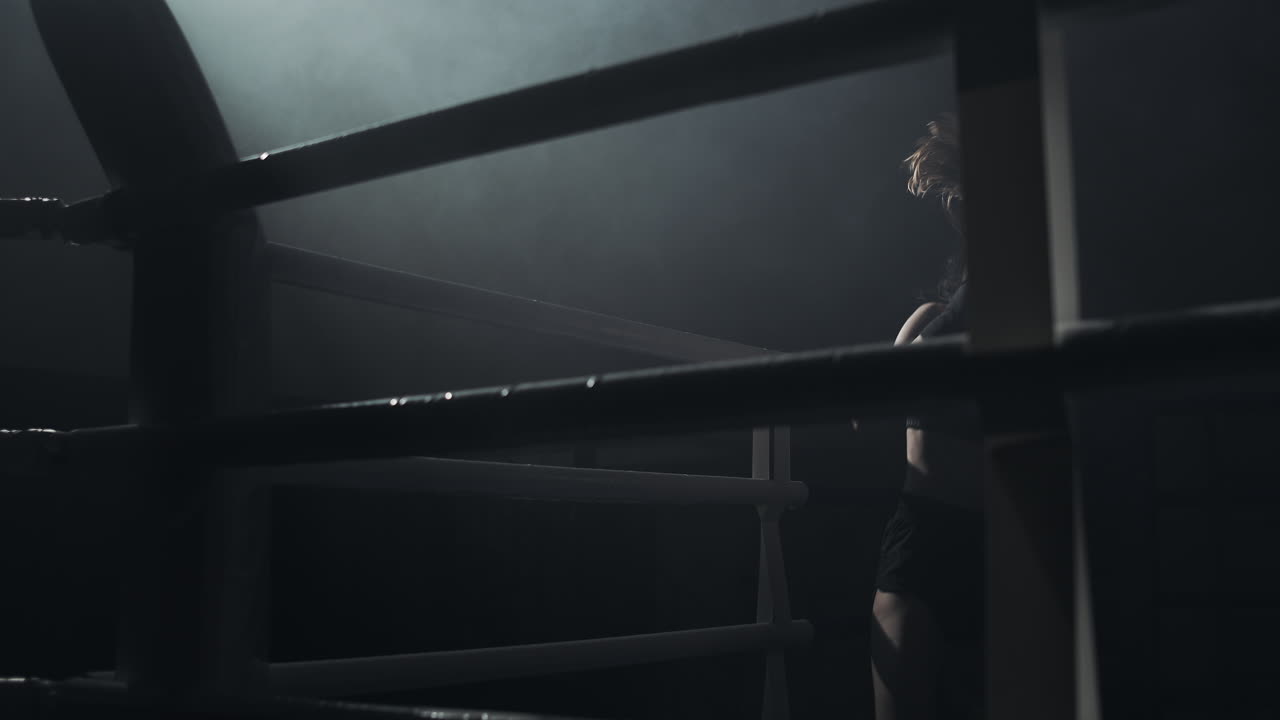 Female Boxer Training in a Dark Ring