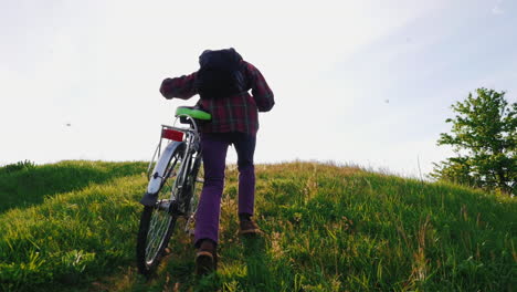man pushes bike up steep hill
