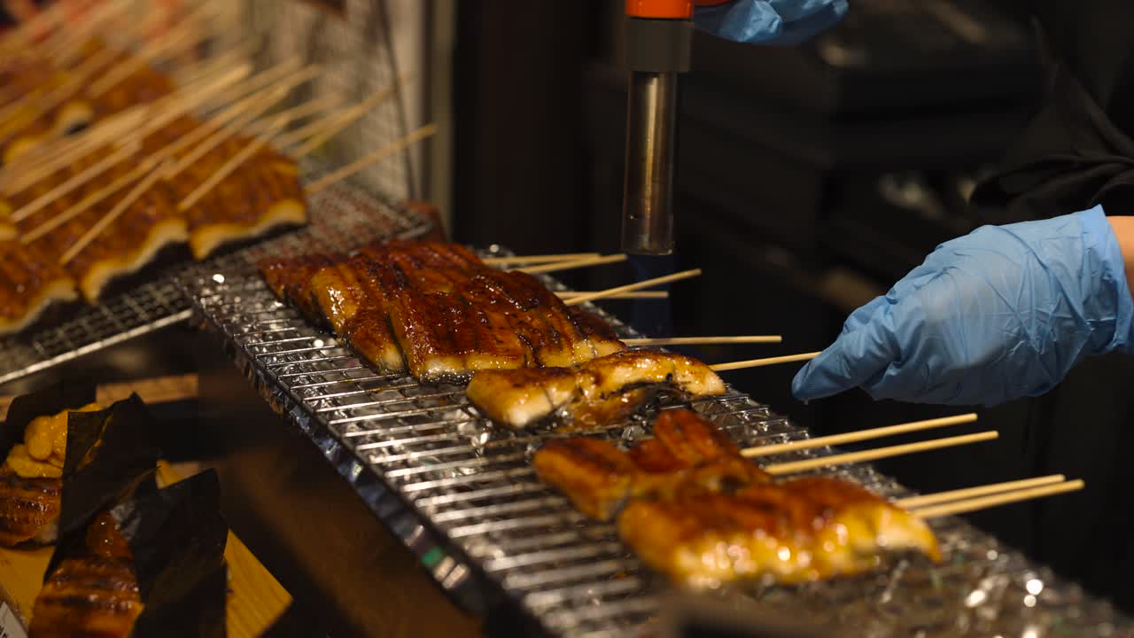 Chef grilling skewered eel over charcoal flames
