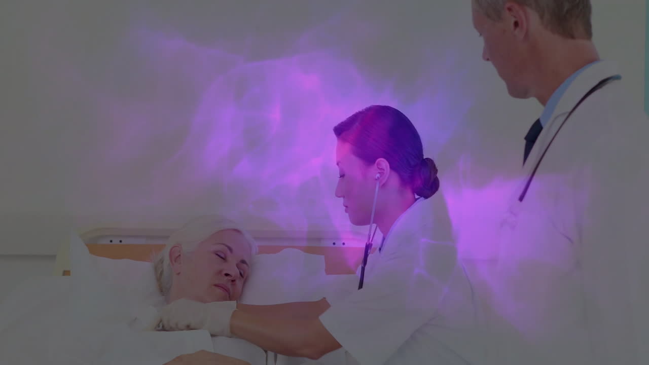 Health pro leaning over senior patient on hospital bed showing animated heart icon and chart