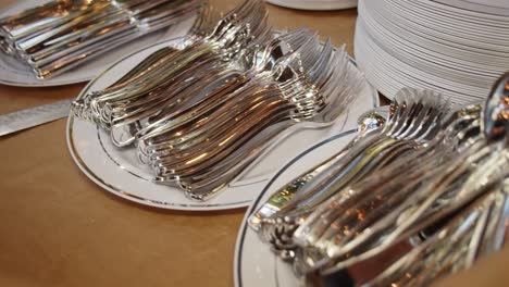 medium shot of metal forks and spoons placed on plates during social event catering in the evening