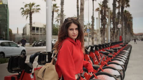 Young-girl-looking-at-the-camera-in-a-bycicle-for-rent-parking