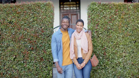 portrait of happy african american couple embracing and standing outside house, slow motion