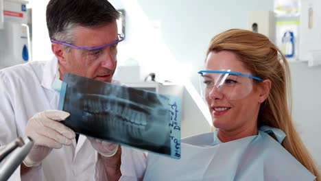 Dentist-and-patient-in-protective-glasses-looking-x-ray-together