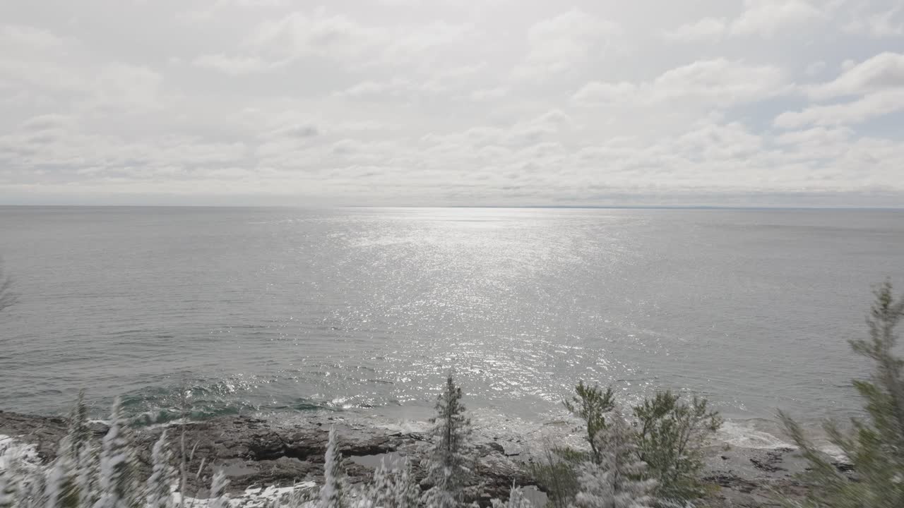 Lake Superior With Shimmering Waters And Snowy Forest On Shore After Snowstorm In Lake County, Minnesota. drone shot