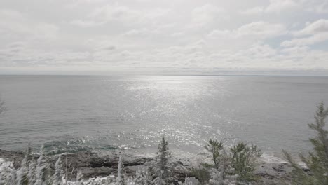lake superior with shimmering waters and snowy forest on shore after snowstorm in lake county, minnesota. drone shot