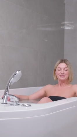 relaxed, beautiful woman lying in a hot tub in a spa salon. a beautician gives a health massage to a client.
