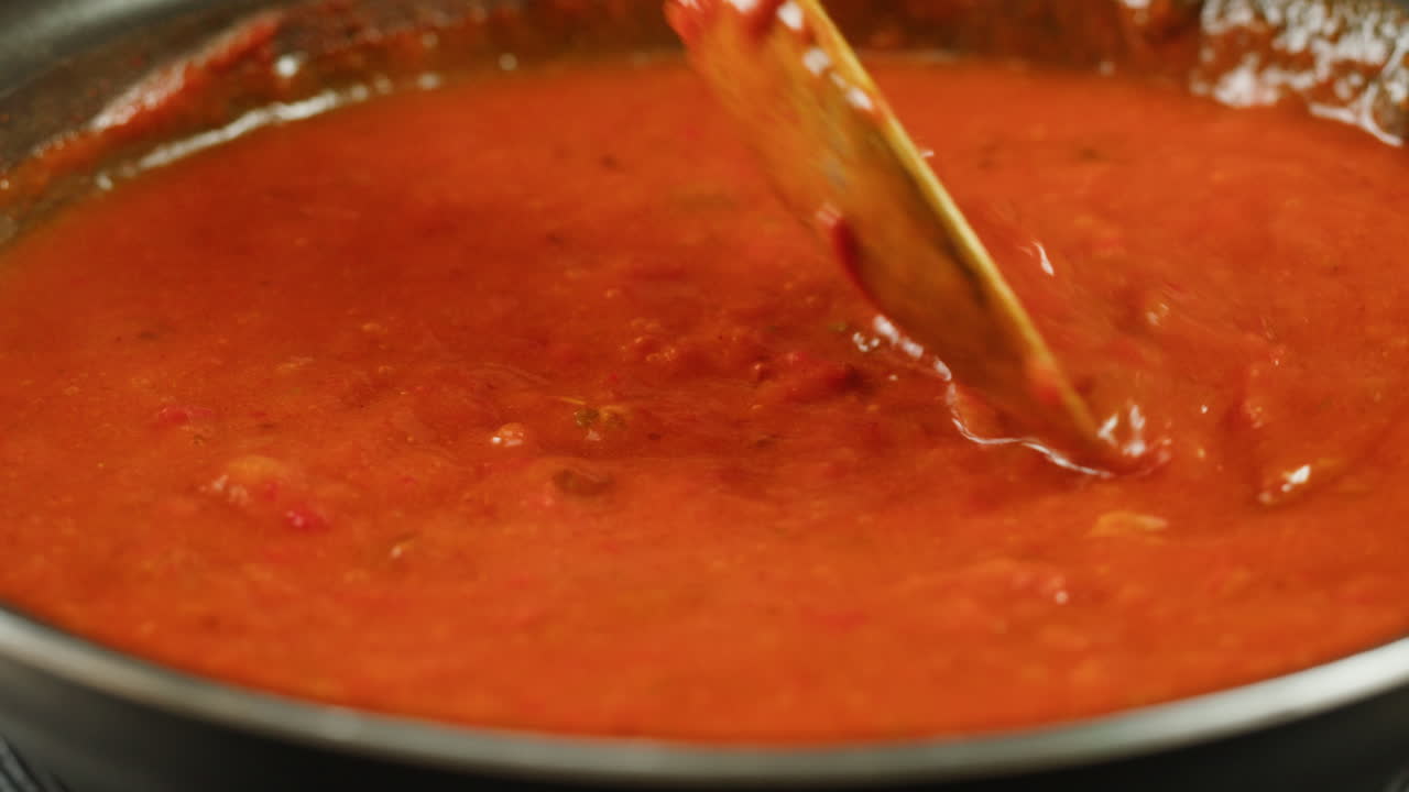 Chicken in tomato sauce is boiling on a frying pan with spices. Cooking tomato sauce curry with chicken fillet. Traditional Italian Mexican Asian dish. High quality studio shot for cafe, restaurant close up.
