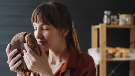 happy woman smelling loaf of freshly baked rye bread