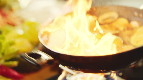 cooking vegetables in a pan with flames