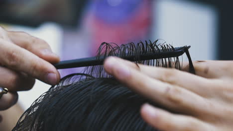 barber does new haircut to client with black hair in salon