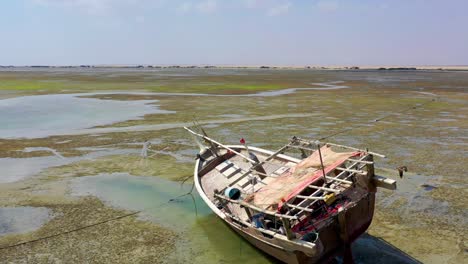 Drone-flying-low-over-the-boat-wreck-on-the-vast-endless-wet-grassland