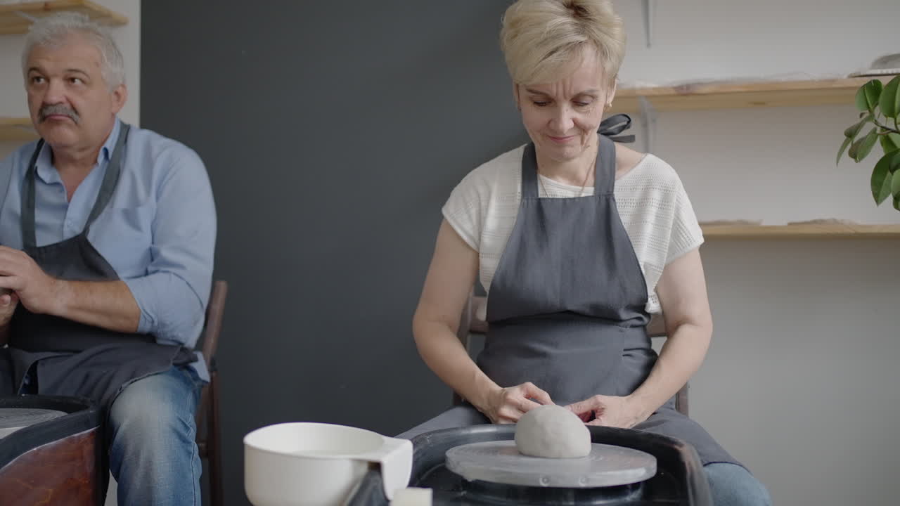 Three elderly people work on a potter's wheel in slow motion