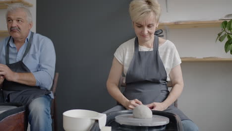 Three-elderly-people-work-on-a-potter's-wheel-in-slow-motion