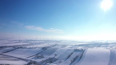 icy cold winter at vast agricultural land with wind turbines at background