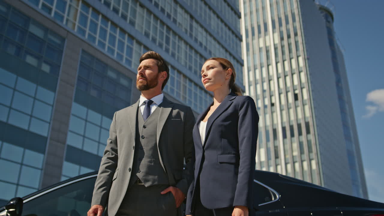 Two business partners posing at urban district in formal suit closeup zoom out.