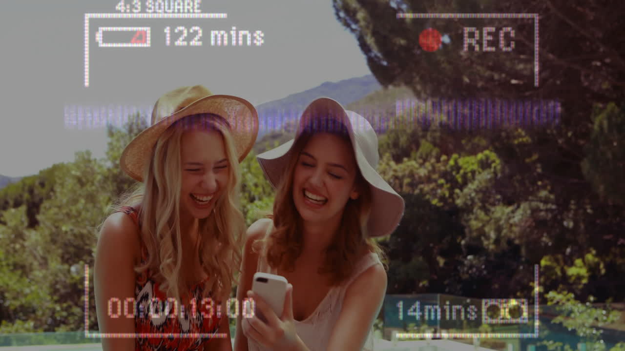 Laughing and looking at smartphone, two women in sun hats with animation